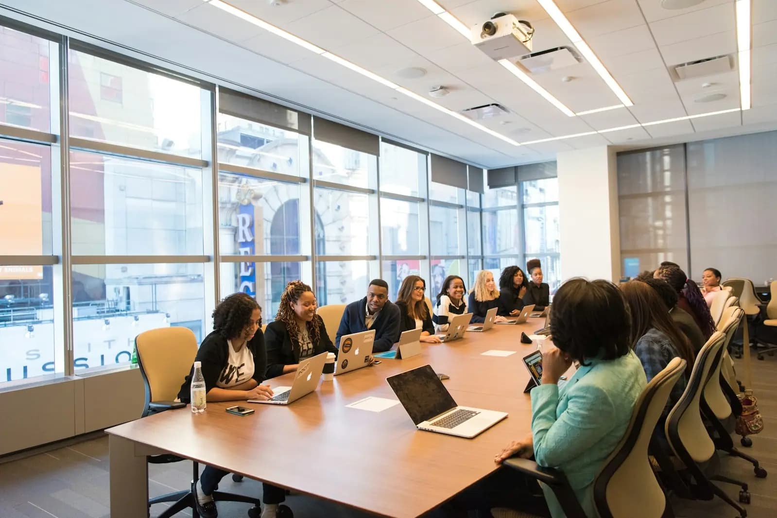 A team meeting around a long conference table with laptops open