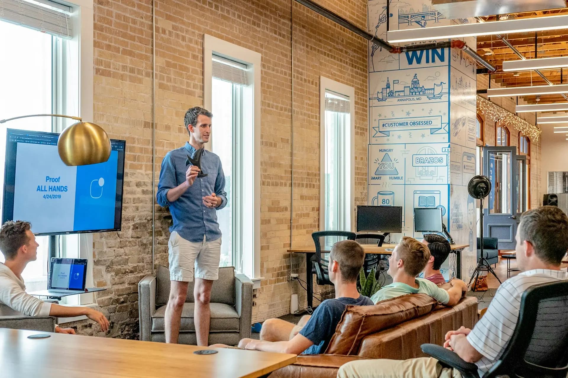 A team listening to a colleague present in a bright loft office
