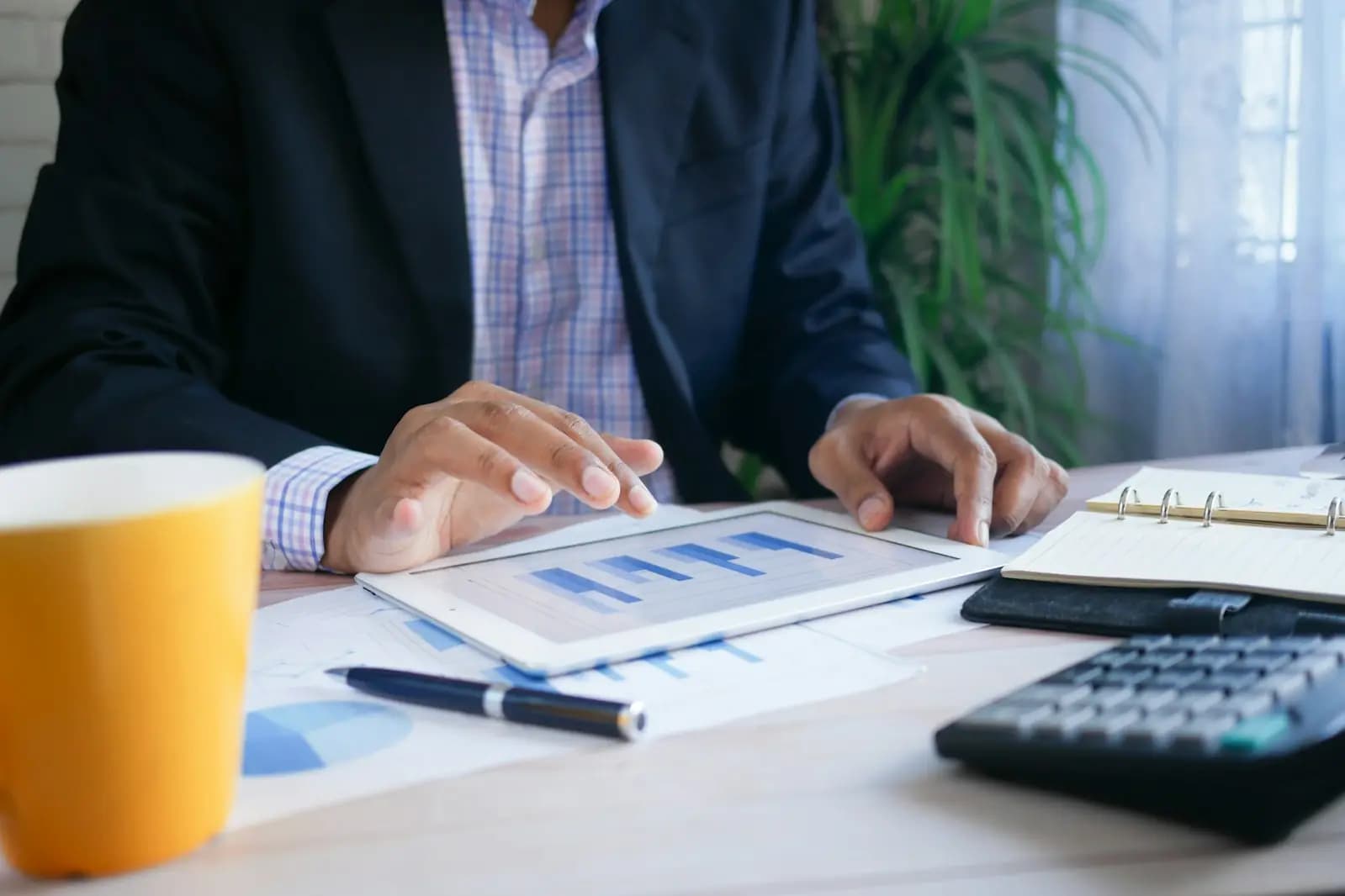 A manager reviewing printed charts with a tablet and calculator on the desk