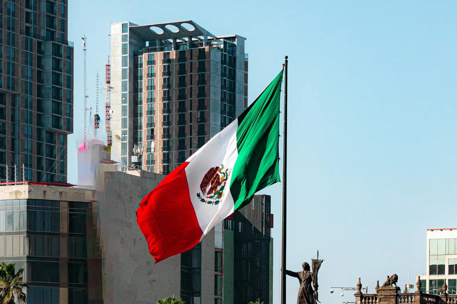 The Mexican flag flying beside modern office towers